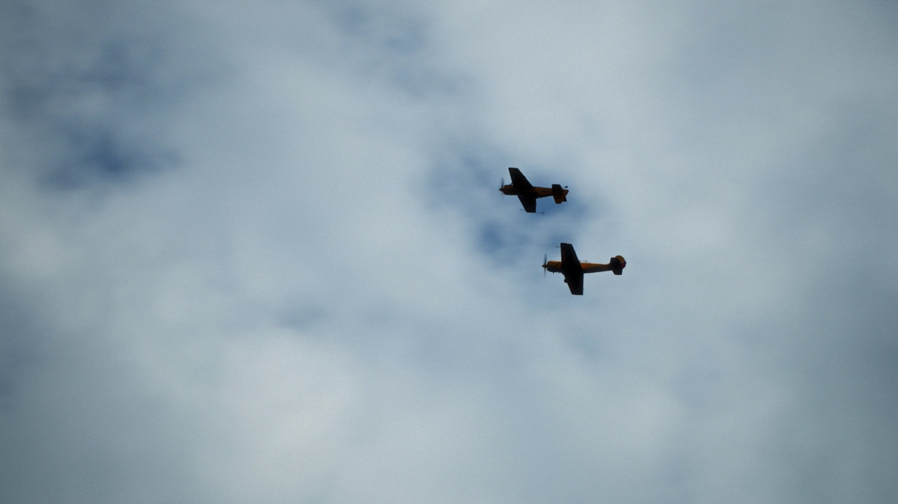 Aerobatic aircraft flying beneath clouds